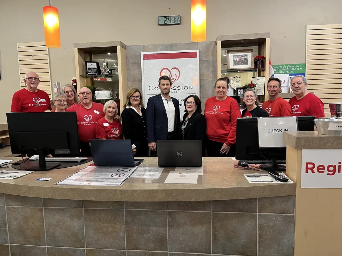 Compassion Society of Halton staff and volunteers in red Compassion shirts gather with guests at the front desk where visits begin.